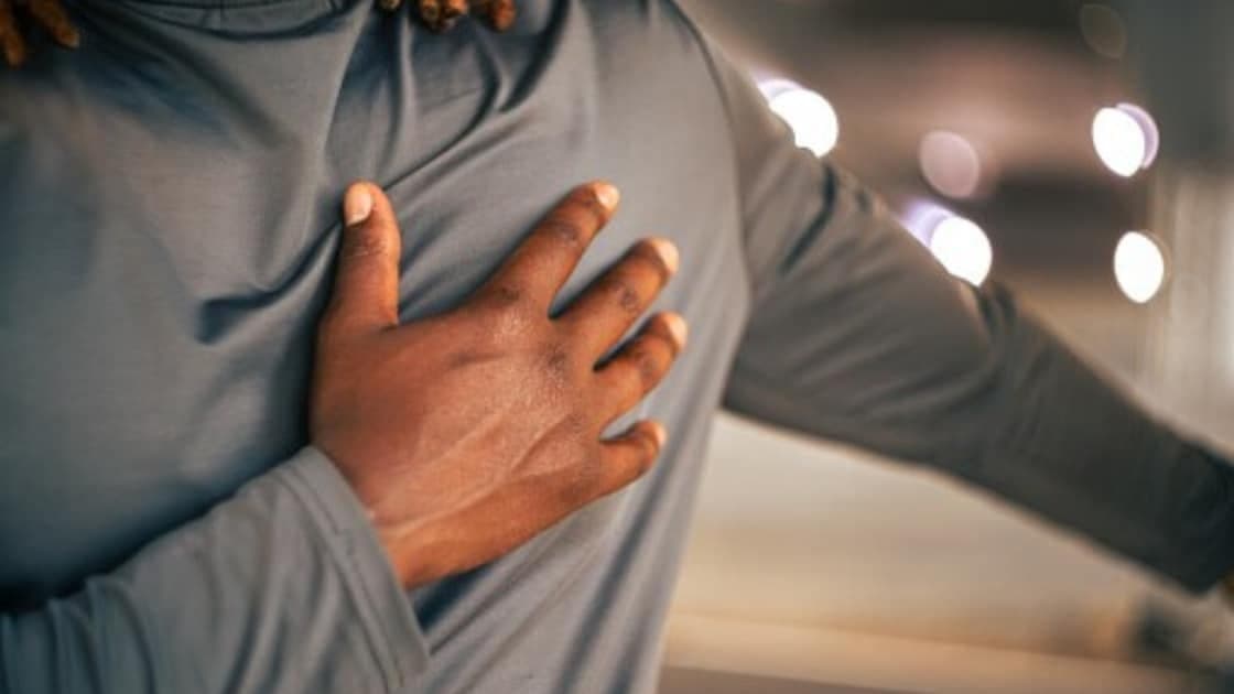 News18 article image: a person clutching their chest, used with Dr. Godbole's heart attack versus cardiac arrest feature